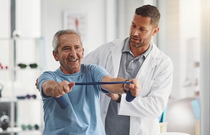 Doctor helping patient stretch with bands